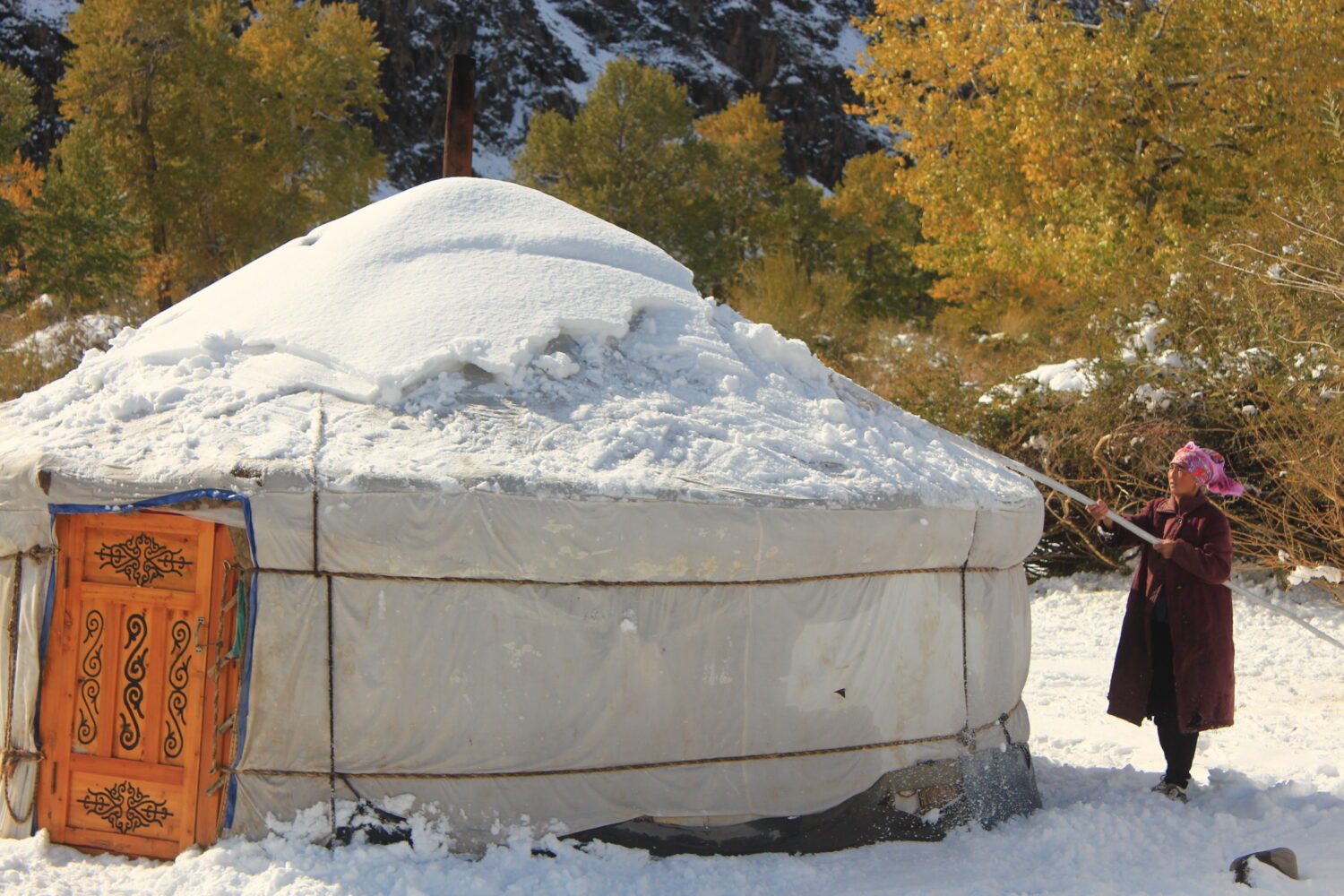 A nomad lady sweeping the snow off her Ger