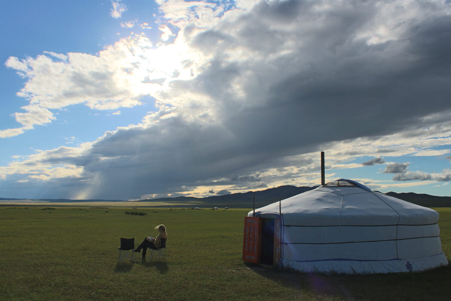 a woman reading a book outside of a ger in Mongolia