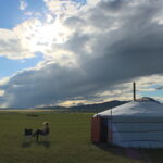 a woman reading a book outside of a ger in Mongolia