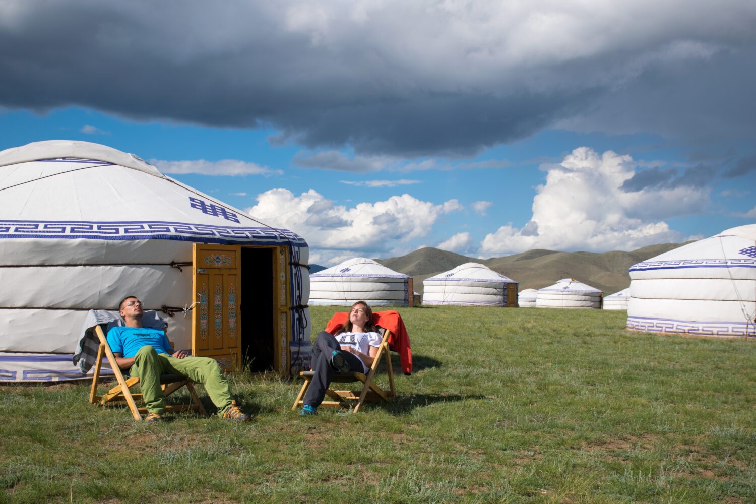 tourists enjoying the sun outside of a ger in orkhon valley, unesco world heritage site, mongolia