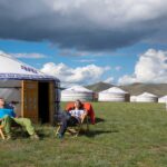 tourists enjoying the sun outside of a ger in orkhon valley, unesco world heritage site, mongolia