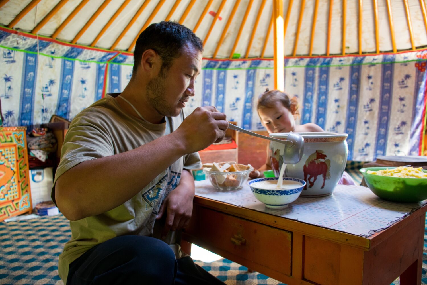 A nomad husband serving a bowl of horse milk for the guests. Meeting a nomad family in Mongolia is an enriching cultural experience that offers insight into the traditional and pastoral way of life. Guests are warmly welcomed into the nomadic ger (yurt), where hospitality is generously extended through shared meals and engaging conversations. Visitors have the chance to witness and participate in daily activities such as milking livestock, making traditional dairy products like airag (fermented mare's milk), and experiencing firsthand the customs and rituals integral to nomadic life. This immersive encounter allows for a deep appreciation of Mongolia's nomadic heritage, fostering meaningful connections between travelers and local communities while providing a glimpse into their resilient, centuries-old lifestyle.