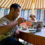 A nomad husband serving a bowl of horse milk for the guests. Meeting a nomad family in Mongolia is an enriching cultural experience that offers insight into the traditional and pastoral way of life. Guests are warmly welcomed into the nomadic ger (yurt), where hospitality is generously extended through shared meals and engaging conversations. Visitors have the chance to witness and participate in daily activities such as milking livestock, making traditional dairy products like airag (fermented mare's milk), and experiencing firsthand the customs and rituals integral to nomadic life. This immersive encounter allows for a deep appreciation of Mongolia's nomadic heritage, fostering meaningful connections between travelers and local communities while providing a glimpse into their resilient, centuries-old lifestyle.